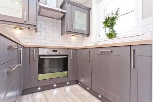 a kitchen with gray cabinets and a window at Coastguard Cottage in Bournemouth