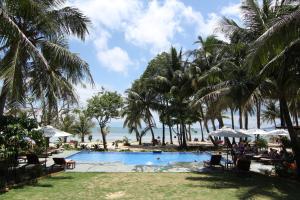 a pool at the beach with palm trees and the ocean at Peppercorn Beach Resort in Phú Quốc