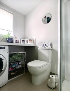 a bathroom with a toilet and a washing machine at The But n Ben in Christchurch