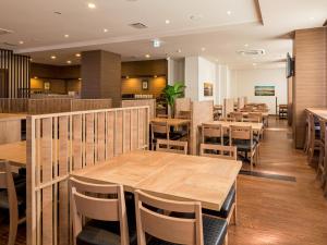 a restaurant with wooden tables and chairs at Hotel Route Inn Minami Yokkaichi in Yokkaichi
