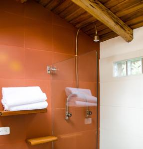 een douche in een badkamer met oranje tegels bij Rukka Lodge in Tumbaco