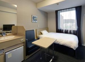 a small hotel room with a bed and a sink at Hotel Route-Inn Kamaishi in Kamaishi