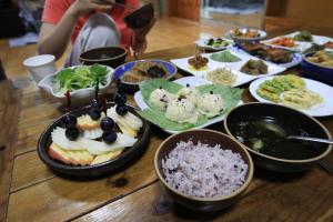 a table with a bunch of plates of food on it at Bangdigareum B&B in Seogwipo