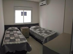 um quarto com duas camas e uma janela em 02 suítes em Capão da Canoa - Ed Maui em Capão da Canoa