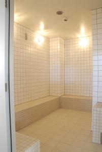 a bathroom with white tiled walls and a tub at Renaissance Tanagura in Shirakawa