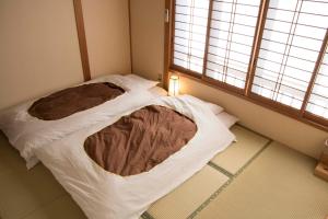 a small room with a bed with a blanket at J-Hoppers Kumano Yunomine Guesthouse in Hongu
