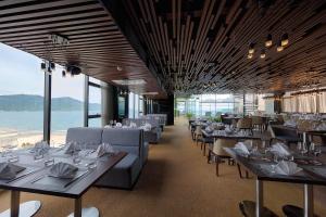 ein Restaurant mit Tischen und Stühlen und Meerblick in der Unterkunft Belle Maison Parosand Da Nang Hotel -managed by H&K Hospitality in Đà Nẵng