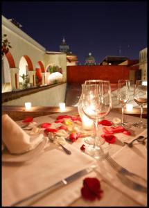 una mesa con copas de vino y rosas. en El Sueño Hotel & Spa, en Puebla