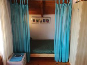 a small bed in a room with blue curtains at Nikos Loft Olympia in Káto Figália