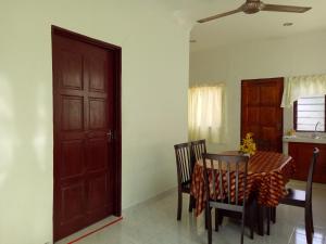 a dining room with a table and chairs and a door at Nas Villaria Langkawi in Pantai Cenang