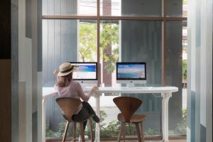a woman sitting at a desk with two computer monitors at Travelodge Pattaya in Pattaya