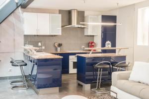 eine Küche mit blauen Schränken und Barhockern in der Unterkunft LE LOFT 67 in Straßburg