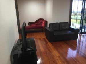 a living room with a couch and a tv and a chair at Glenaire Apartments at Frazer St in Strahan