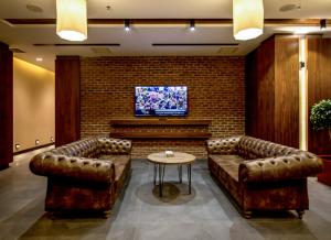 a lobby with two leather couches and a tv at Vista Hotel in Mezitli