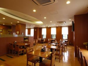 una sala da pranzo con tavoli e sedie in legno di Hotel Route-Inn Matsusaka Ekihigashi a Matsuzaka