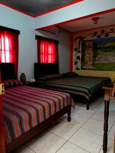 two beds in a room with red curtains at Hotel & Hostal Yaxkin Copan in Copán Ruinas