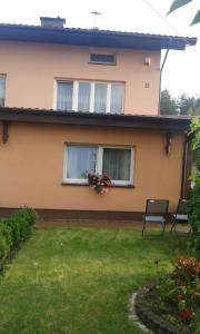 una casa con dos ventanas y un banco en el patio en Noclegi Jagoda, en Stromiec