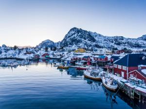 un puerto cubierto de nieve con barcos en el agua en The Tide - Rorbuer, en Sørvågen