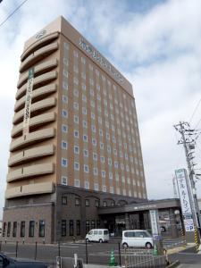 un edificio de hotel con coches estacionados frente a él en Hotel Route-Inn Higashimuroran Ekimae, en Muroran