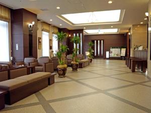 vestíbulo con zona de espera con sofás y plantas en Hotel Route-Inn Higashimuroran Ekimae, en Muroran