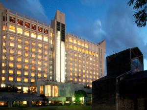 un gran edificio con sus luces encendidas por la noche en Hotel Crown Palais Kitakyushu, en Kitakyushu