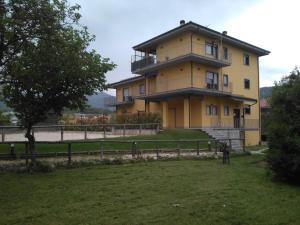 una gran casa amarilla con una valla delante en Il Boscaiolo Affittacamere, en Preturo