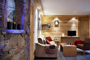 a living room with a couch and a stone wall at CGH Résidences & Spas Le Lodge Hemera in La Rosière