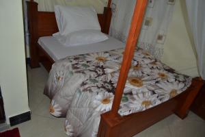 un piccolo letto con struttura in legno e un letto a fiori di Barcelona Lodge a Bagamoyo
