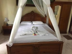 Una cama con dos toallas de cisne. en Batan Duren House en Ubud