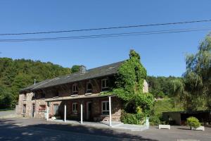 an old stone building with a tree on the side of it at Aux 3 Canards in Stoumont
