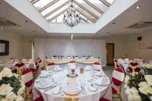 a banquet room with white tables and chairs and a chandelier at Golden Lion Hotel in Rugby