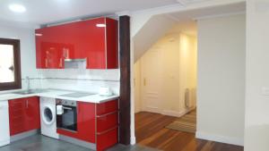 a kitchen with red cabinets and a white appliance at Mundaka Sea Flat in Mundaka