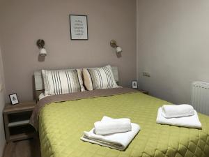 - une chambre avec un lit vert et des serviettes dans l'établissement Origo Vendégház, à Sárospatak