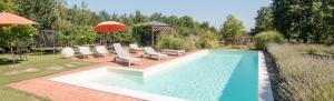 a swimming pool with chairs and an umbrella at La casetta di Lu in Cellarengo