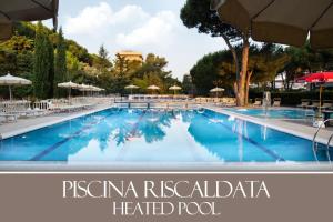 uma grande piscina com cadeiras e guarda-sóis em Park Hotel Marinetta - Beach & Spa em Marina di Bibbona