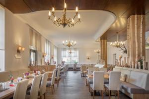 une salle à manger avec des tables et des chaises ainsi qu'un lustre dans l'établissement Hotel Vier Jahreszeiten, à Garmisch-Partenkirchen