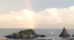 a rainbow over a small island in the ocean at La Magnolia in Acitrezza