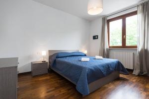 una camera bianca con un letto blu e una finestra di Dimora Ronchi a Ronchi