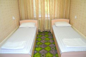 two beds in a small room with green at Osh Guesthouse in Osh