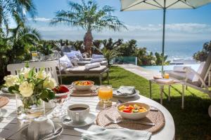 una mesa con comida y vistas al océano en Ocean Watch Guest House en Plettenberg Bay