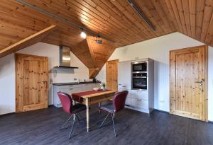 cocina con techo de madera, mesa de madera y sillas en Ferienwohnung Waldblick, en Kleinsteinhausen