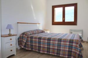 1 dormitorio con 1 cama con manta a cuadros y ventana en Apartament a Capafonts - "Ribatell", en Capafons