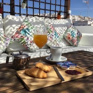 una mesa con un vaso de zumo de naranja y una bandeja de pan en Hotel Posada de las Cuevas, en Arcos de la Frontera