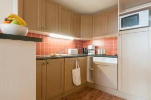 a kitchen with brown cabinets and a white refrigerator at Résidence Pierre & Vacances Le Belmont in Arc 1800
