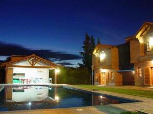 a swimming pool in front of a house at night at Residencial del Golf in Alta Gracia