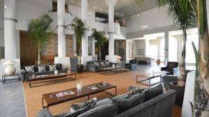 a large lobby with couches and tables and palm trees at Fairplay Golf & Spa Resort in Benalup Casas Viejas