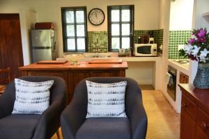 una cocina con 2 sillas y un reloj en la pared en Molly's Cottage, en Graskop