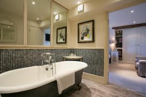 a bathroom with a tub and a mirror at The Kingham Plough in Kingham