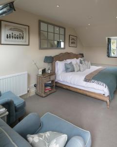 een slaapkamer met een groot bed en een bank bij The Kingham Plough in Kingham