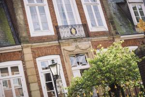 un bâtiment avec une horloge sur son côté dans l'établissement Burghotel Haselünne, à Haselünne